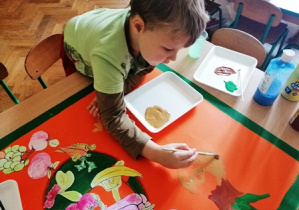 chłopiec maluje farbami cebulę
